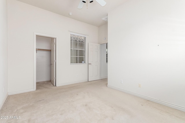 unfurnished bedroom featuring a closet, baseboards, a ceiling fan, carpet floors, and a walk in closet