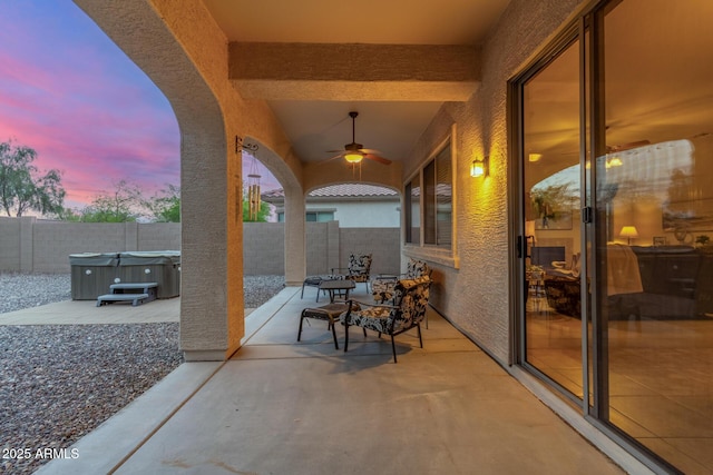 view of patio with a fenced backyard, a ceiling fan, and a hot tub