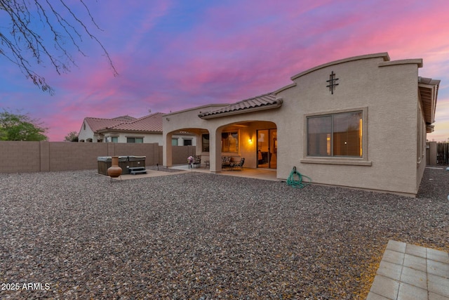 back of house at dusk featuring a patio area, a fenced backyard, and stucco siding