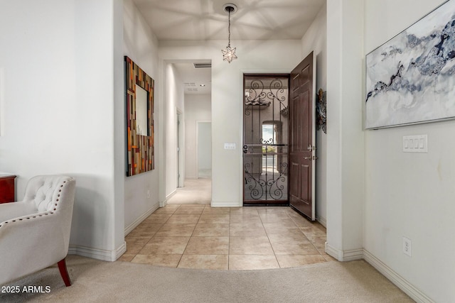hallway featuring light carpet, light tile patterned floors, baseboards, and visible vents
