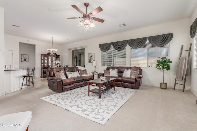 living room featuring light carpet, ceiling fan with notable chandelier, baseboards, and visible vents