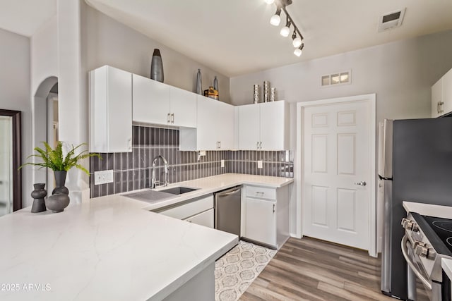kitchen featuring tasteful backsplash, light wood-style flooring, visible vents, appliances with stainless steel finishes, and a sink