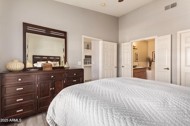bedroom featuring light wood-style flooring, ensuite bathroom, and visible vents