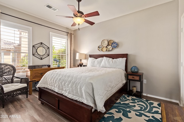 bedroom featuring visible vents, baseboards, ceiling fan, and wood finished floors