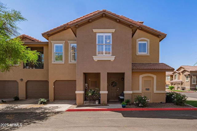view of front facade featuring a tile roof, an attached garage, driveway, and stucco siding