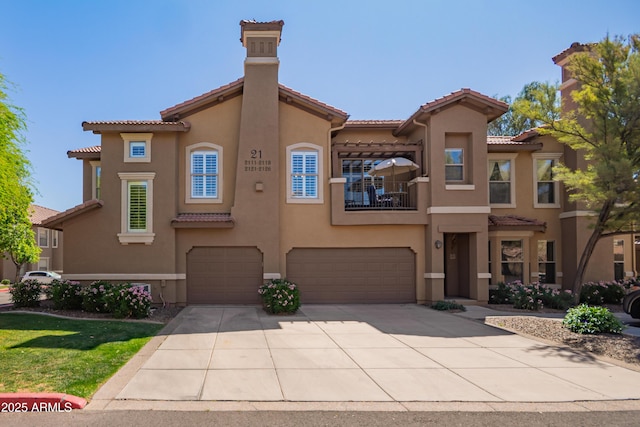 view of front facade featuring a tiled roof, an attached garage, concrete driveway, stucco siding, and a balcony