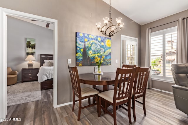 dining area with a notable chandelier, baseboards, vaulted ceiling, and wood finished floors
