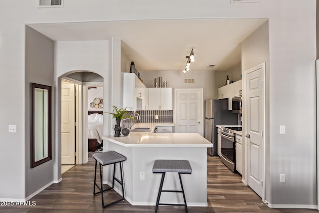 kitchen with visible vents, a sink, a peninsula, stainless steel appliances, and a breakfast bar area