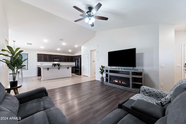 living room featuring light wood-type flooring, vaulted ceiling, and ceiling fan