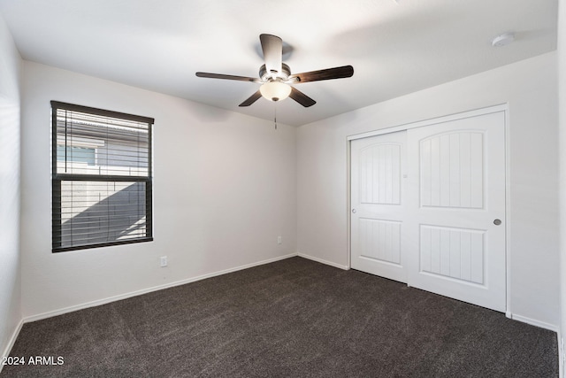 unfurnished bedroom with dark carpet, a closet, and ceiling fan