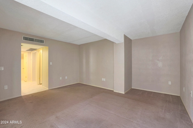 unfurnished room with carpet and a textured ceiling