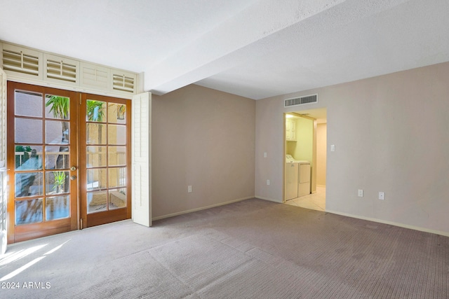 unfurnished room featuring beam ceiling, light carpet, french doors, and independent washer and dryer