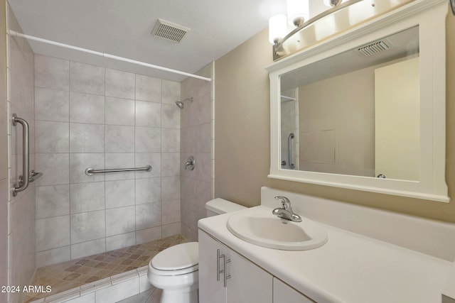 bathroom featuring vanity, toilet, and tiled shower