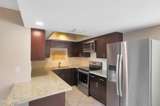 kitchen with kitchen peninsula, sink, appliances with stainless steel finishes, and a textured ceiling