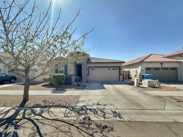 view of front facade with a tile roof, an attached garage, driveway, and stucco siding