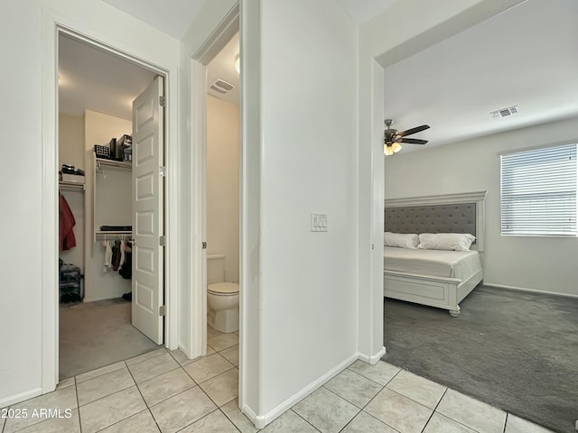 hall featuring light tile patterned floors, light colored carpet, and visible vents