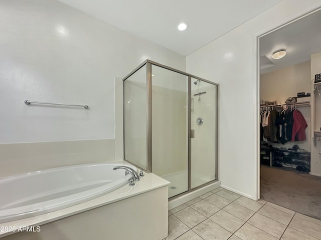 bathroom featuring a walk in closet, a shower stall, a bath, and tile patterned flooring