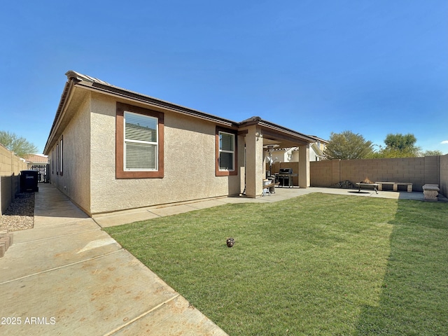 rear view of house featuring a patio area, stucco siding, a lawn, and a fenced backyard