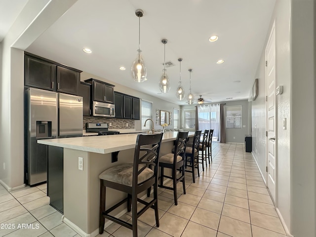 kitchen featuring visible vents, a large island, stainless steel appliances, light countertops, and decorative backsplash