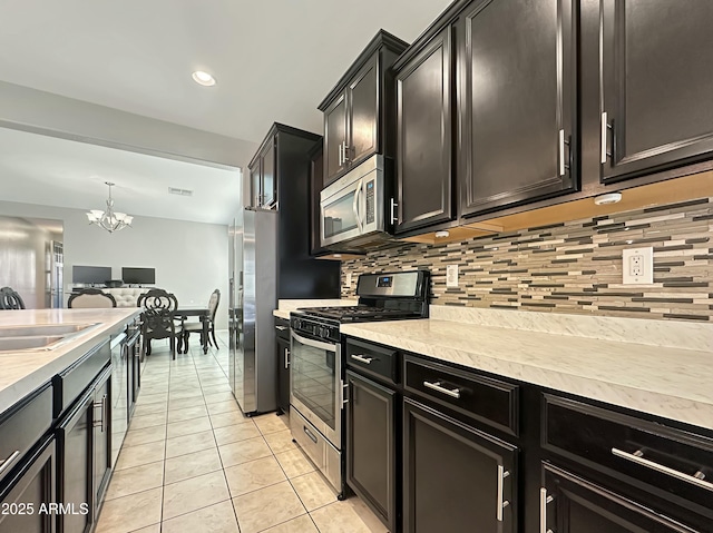 kitchen with backsplash, light countertops, appliances with stainless steel finishes, light tile patterned flooring, and a sink