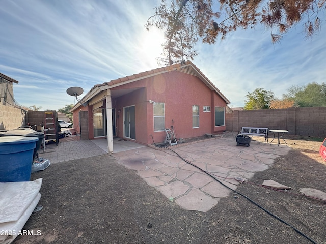 back of property featuring an outdoor fire pit and a patio