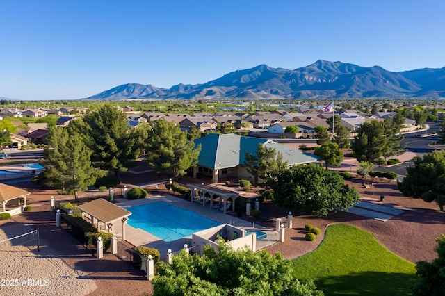 community pool with a residential view, a mountain view, and a patio