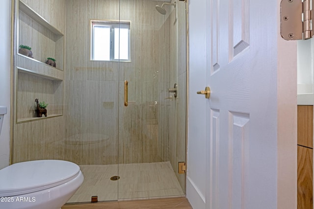 bathroom with a shower with shower door and toilet