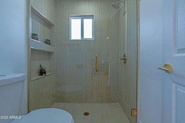 bathroom featuring a shower with shower door and toilet