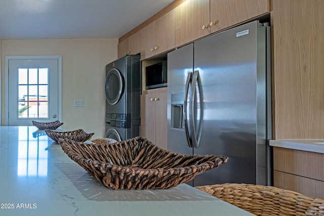 kitchen featuring stacked washer and dryer, stainless steel appliances, and light brown cabinets