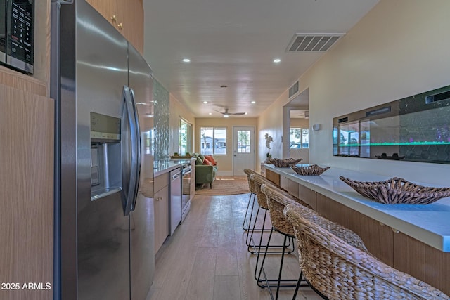 kitchen featuring appliances with stainless steel finishes, light wood-type flooring, and a kitchen breakfast bar