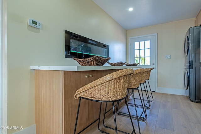 kitchen with light wood-type flooring, a breakfast bar area, and stacked washer / dryer