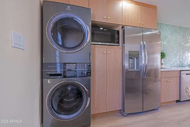 clothes washing area with stacked washer and clothes dryer and light hardwood / wood-style flooring