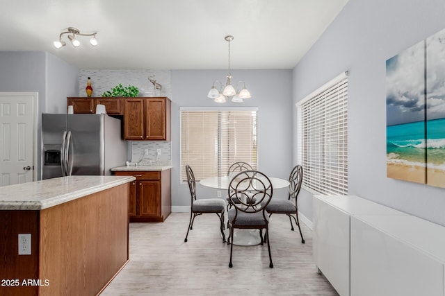 dining space with light wood-style flooring, baseboards, and an inviting chandelier