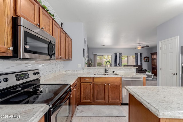 kitchen featuring decorative backsplash, brown cabinets, a peninsula, stainless steel appliances, and a sink