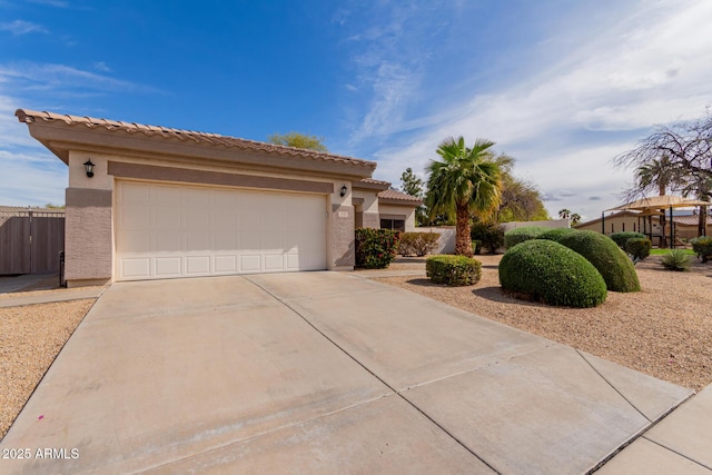 view of front facade with fence, a tile roof, concrete driveway, stucco siding, and a garage