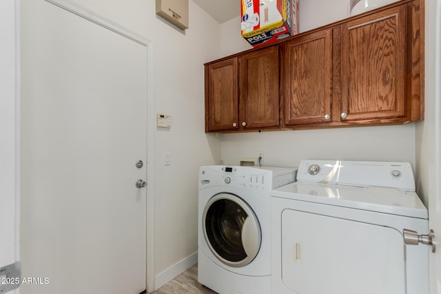 clothes washing area with cabinet space, washing machine and dryer, and baseboards