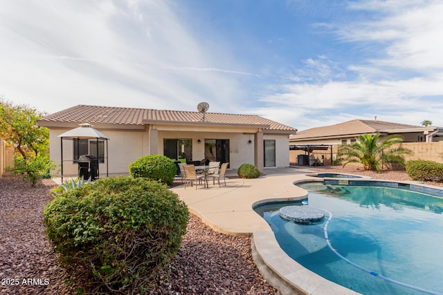 back of property with a patio area, an in ground hot tub, a tile roof, and fence