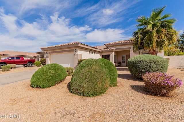 mediterranean / spanish home with a garage, concrete driveway, stucco siding, and a tile roof