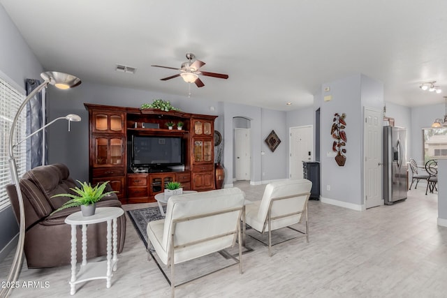 living area with light wood-style flooring, a ceiling fan, visible vents, and baseboards