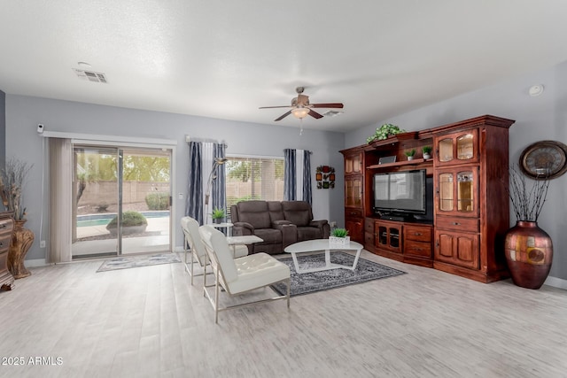 living area with light wood finished floors, visible vents, baseboards, and a ceiling fan