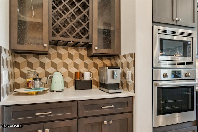 15711 S 11th Ave, Phoenix, AZ 85045 - kitchen featuring stainless steel appliances, glass insert cabinets, decorative backsplash, and light countertops