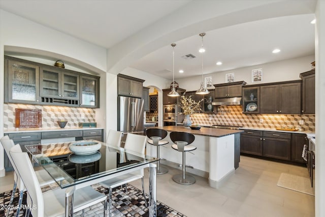 15711 S 11th Ave, Phoenix, AZ 85045 - kitchen featuring under cabinet range hood, stainless steel appliances, arched walkways, backsplash, and dark brown cabinetry