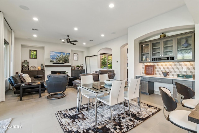 15711 S 11th Ave, Phoenix, AZ 85045 - living room with light tile patterned floors, arched walkways, recessed lighting, a warm lit fireplace, and a ceiling fan