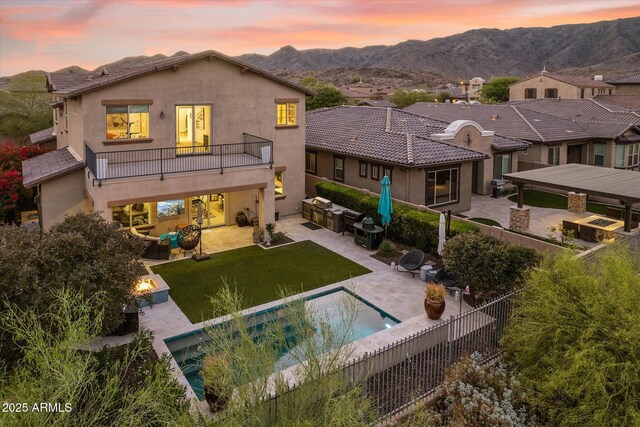 15711 S 11th Ave, Phoenix, AZ 85045 - back of property at dusk featuring a patio area, an outdoor living space with a fire pit, a balcony, stucco siding, and a mountain view