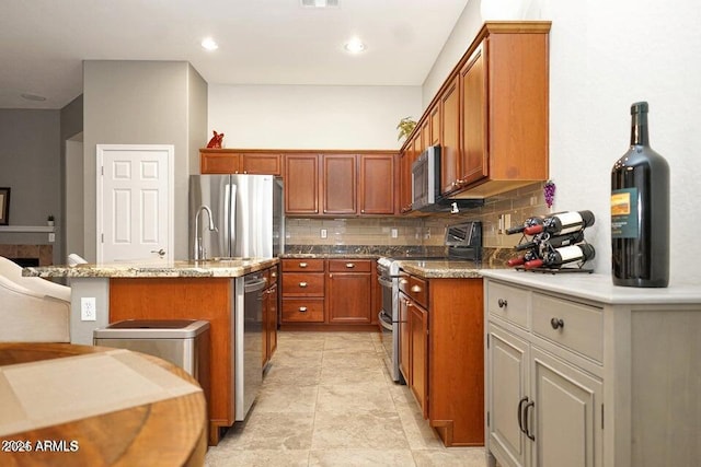 kitchen featuring stainless steel appliances, light stone countertops, a kitchen island with sink, and decorative backsplash