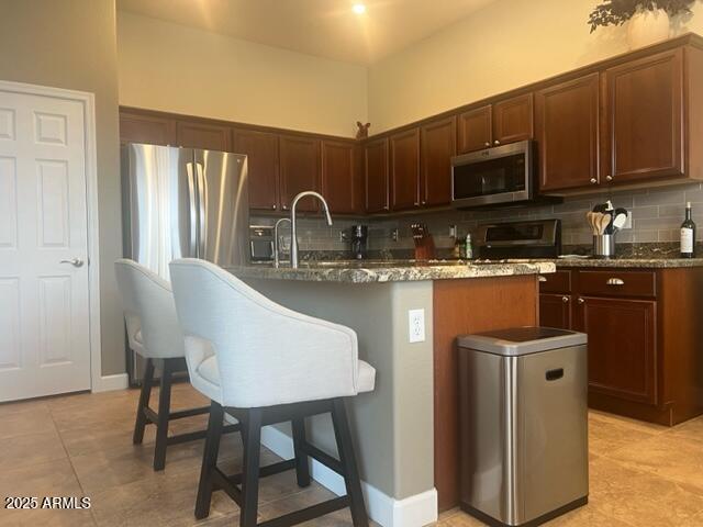 kitchen featuring appliances with stainless steel finishes, sink, a center island with sink, and dark stone counters