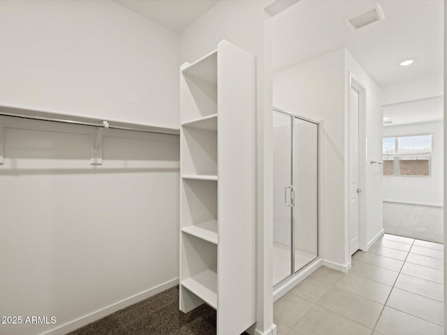 walk in closet featuring tile patterned flooring, visible vents, and carpet