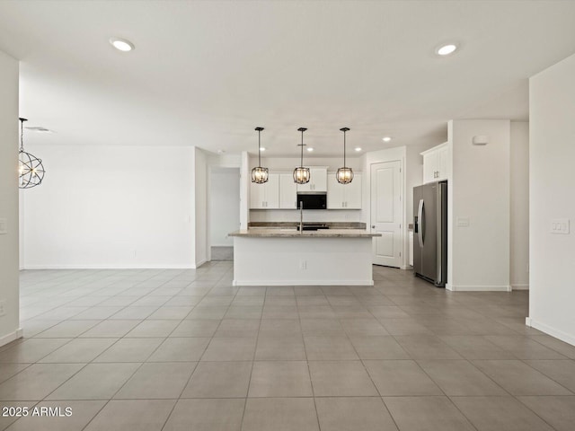 kitchen featuring recessed lighting, light stone countertops, stainless steel fridge, open floor plan, and white cabinetry