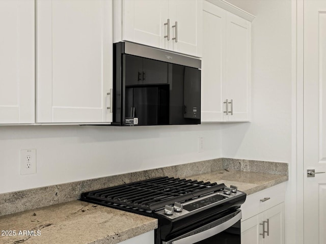 kitchen featuring white cabinets, stainless steel range with gas stovetop, and light stone counters