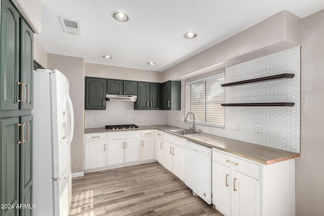 kitchen with white appliances, backsplash, white cabinets, sink, and light hardwood / wood-style flooring